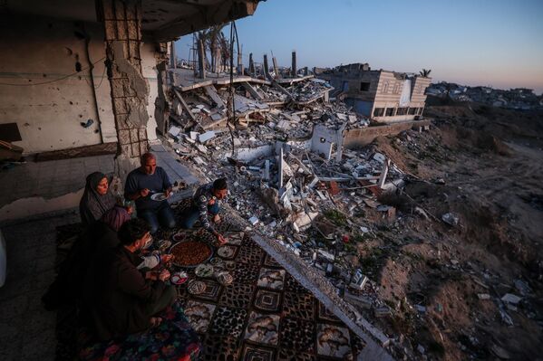 Una familia palestina del distrito de Sheikh Ajlin, en el sur de la ciudad de Gaza, rompe el ayuno sobre los escombros de su casa demolida por las fuerzas israelíes. - Sputnik Mundo