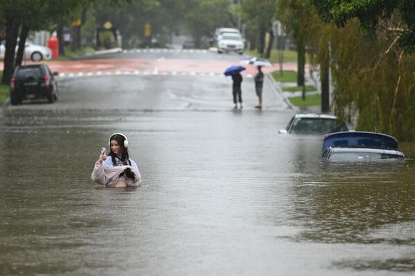 Una residente camina a lo largo de una calle inundada en Edmonstone, en el suburbio de Newmarket el 9 de marzo 2025 en Brisbane, Australia.  - Sputnik Mundo