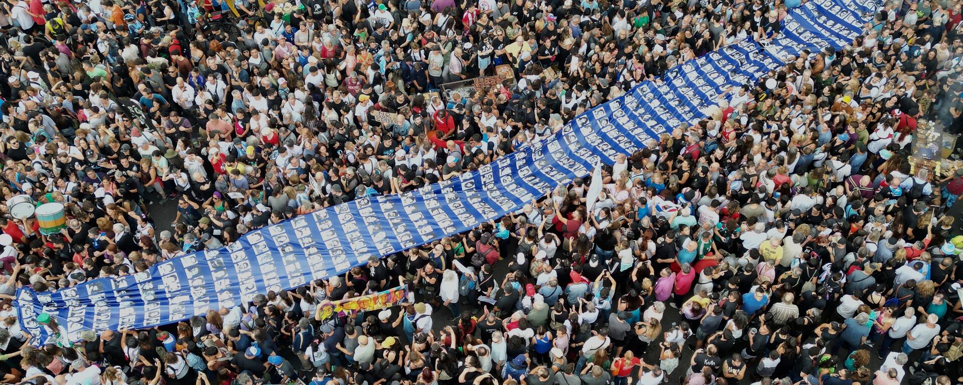 Manifestantes portan una pancarta con fotos de personas desaparecidas durante la dictadura militar argentina (1976-1983) en una marcha en conmemoración del aniversario del golpe de Estado de 1976, en Buenos Aires, Argentina, el lunes 24 de marzo de 2025. (Foto AP/Rodrigo Abd) - Sputnik Mundo, 1920, 25.03.2025