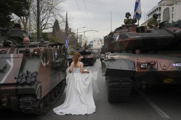 Una mujer vestida de novia camina entre tanques durante una sesión fotográfica en Atenas antes de un desfile militar para conmemorar el inicio de la guerra de independencia de Grecia, en 1821, contra el dominio otomano de 400 años. Una mujer vestida de novia camina entre tanques durante una sesión fotográfica en Atenas antes de un desfile militar para conmemorar el inicio de la guerra de independencia de Grecia, en 1821, contra el dominio otomano de 400 años. - Sputnik Mundo