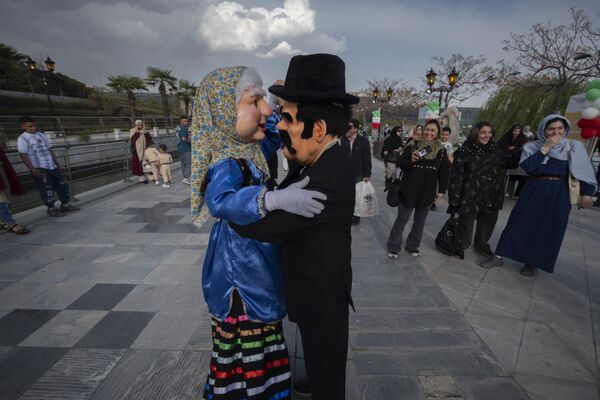 Dos enmascarados interpretan los papeles de un hombre y una mujer tradicionales iraníes y bailan en una ceremonia de izado de bandera con motivo del Día Nacional de Irán. Dos enmascarados interpretan los papeles de un hombre y una mujer tradicionales iraníes y bailan en una ceremonia de izado de bandera con motivo del Día Nacional de Irán. - Sputnik Mundo