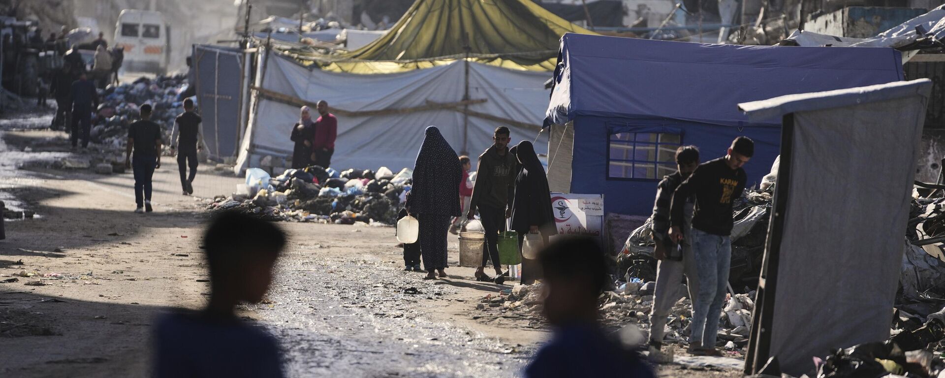 Palestinos desplazados llevan agua junto a los escombros en Jabaliya, Franja de Gaza. - Sputnik Mundo, 1920, 06.04.2025