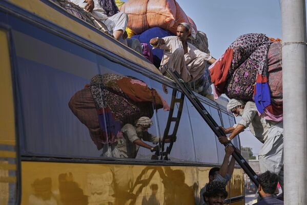 El proceso de carga de las pertenencias de los refugiados afganos sobre el techo de un autobús en la ciudad pakistaní de Karachi. El proceso de carga de las pertenencias de los refugiados afganos sobre el techo de un autobús en la ciudad pakistaní de Karachi. - Sputnik Mundo