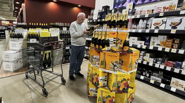 Un comprador revisa el costo de una botella de vino espumoso español de venta en una tienda de Niles, Illinois, EEUU - Sputnik Mundo