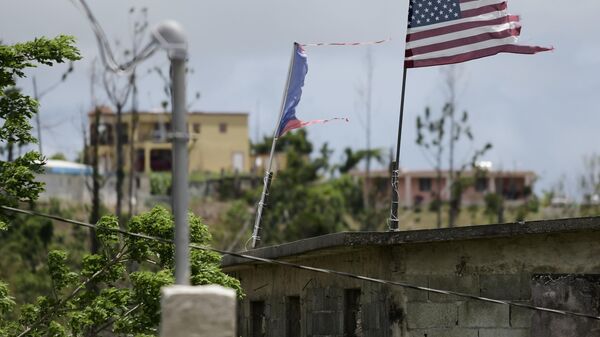 Banderas deterioradas de Estados Unidos y Puerto Rico ondean en un tejado ocho meses después del paso del huracán María en el Barrio Jacana Piedra Blanca de Yabucoa, en Puerto Rico, el 16 de mayo de 2018.  - Sputnik Mundo