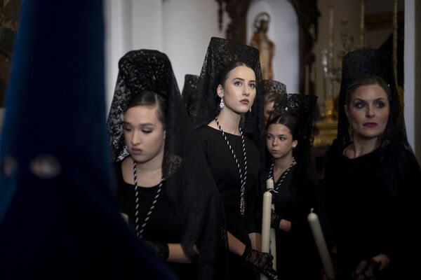 Mujeres vestidas con mantillas tradicionales, preparadas para participar en la procesión de la cofradía Estrella durante la Semana Santa en la ciudad española de Málaga. Mujeres vestidas con mantillas tradicionales, preparadas para participar en la procesión de la cofradía Estrella durante la Semana Santa en la ciudad española de Málaga. - Sputnik Mundo