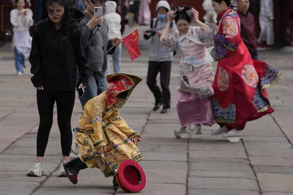 Un niño vestido de emperador chino persigue su corona, arrastrada por el fuerte viento en Pekín, China. Un niño vestido de emperador chino persigue su corona, arrastrada por el fuerte viento en Pekín, China. - Sputnik Mundo
