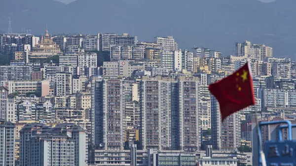 Una bandera nacional china ondea frente a los altos edificios residenciales del condado de Wushan, en la municipalidad de Chongqing, suroeste de China, el miércoles 21 de mayo de 2025. (Foto AP/Andy Wong) - Sputnik Mundo