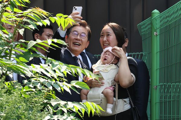 Las elecciones presidenciales de 2025 en Corea del Sur se celebrarán el 3 de junio, tras la destitución del presidente Yoon Suk Yeol en diciembre de 2024.   En la foto: el candidato presidencial del Partido Demócrata, Lee Jae-myung, posando con una simpatizante tras votar anticipadamente el 29 de mayo. - Sputnik Mundo