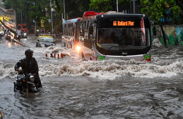Transporte público circulando por una vía inundada tras las fuertes lluvias en la ciudad india de Mumbai. - Sputnik Mundo