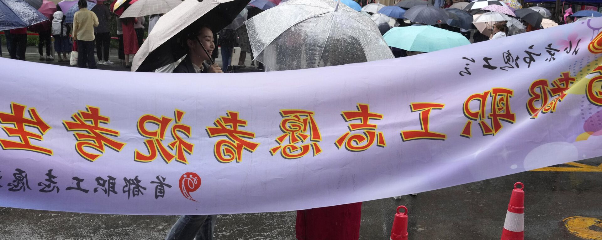 Padres y maestros esperan afuera de una escuela donde los estudiantes realizan el examen nacional anual de ingreso a la universidad, también conocido como Gaokao, mientras llueve en Pekín, el viernes 7 de junio de 2024.  - Sputnik Mundo, 1920, 06.06.2025
