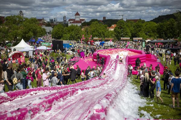 Personas se deslizan por un tobogán acuático hacia un tazón gigante de sopa durante el festival Pink Soup Fest en la capital lituana, Vilna. Personas se deslizan por un tobogán acuático hacia un tazón gigante de sopa durante el festival Pink Soup Fest en la capital lituana, Vilna. - Sputnik Mundo