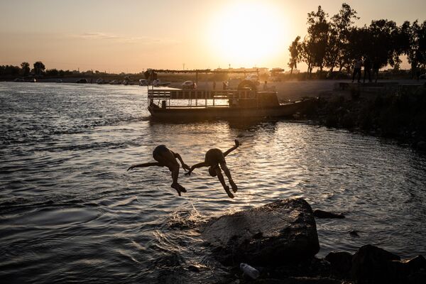 Niños se zambullen en el agua a orillas del río Éufrates, cerca de la ciudad siria de Raqa. Niños se zambullen en el agua a orillas del río Éufrates, cerca de la ciudad siria de Raqa. - Sputnik Mundo