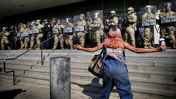 Un manifestante frente a una línea de la Guardia Nacional que protege un edificio federal en el centro de Los Ángeles el 9 de junio de 2025. - Sputnik Mundo