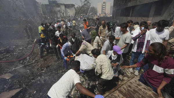 Rescatistas llevan el cuerpo de una víctima de un avión que se estrelló en la ciudad noroccidental india de Ahmedabad, en el estado de Gujarat, el 12 de junio de 2025. - Sputnik Mundo