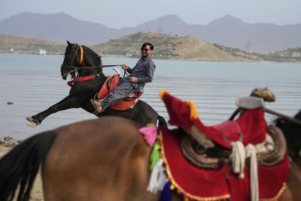 Un hombre montando a caballo a orillas de un lago en las afueras de la capital afgana, Kabul. - Sputnik Mundo