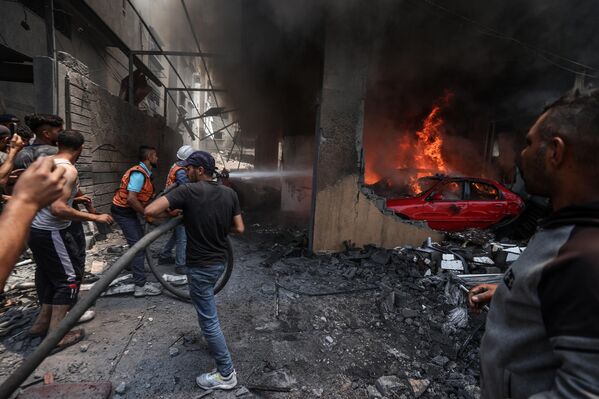 Operación de extinción de incendios y búsqueda y rescate tras los ataques aéreos israelíes contra edificios residenciales en la Franja de Gaza. - Sputnik Mundo