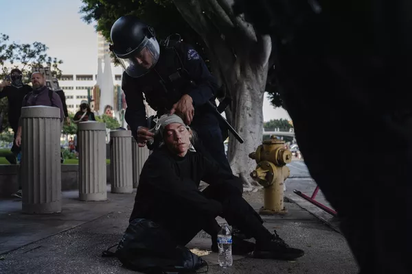 Un agente de la Policía ayuda a una manifestante atropellada por un caballo de los servicios policiales durante los enfrentamientos con las fuerzas del orden en Los Ángeles. Un agente de la Policía ayuda a una manifestante atropellada por un caballo de los servicios policiales durante los enfrentamientos con las fuerzas del orden en Los Ángeles. - Sputnik Mundo