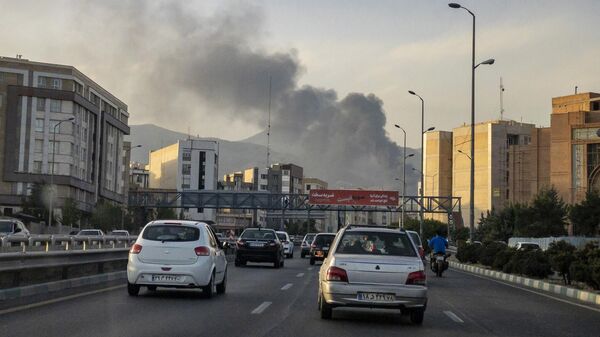Vehículos circulan por una carretera mientras sale humo tras un ataque israelí en Teherán, Irán, el 16 de junio de 2025 Vehículos circulan por una carretera mientras sale humo tras un ataque israelí en Teherán, Irán, el 16 de junio de 2025 - Sputnik Mundo