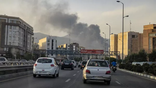 Vehículos circulan por una carretera mientras sale humo tras un ataque israelí en Teherán, Irán, el 16 de junio de 2025 - Sputnik Mundo