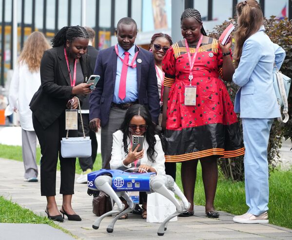 El mandatario de Indonesia, el representante de Baréin, el vice primer ministro del Consejo de Estado de la República Popular China y el vicepresidente de Sudáfrica participarán en la sesión plenaria del SPIEF junto con Putin. En la foto: Los participantes observan a un perro robot caminando por la zona del foro. - Sputnik Mundo