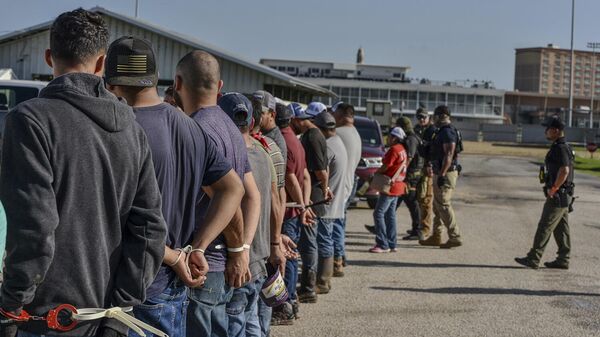 Trabajadores esposados después de ser arrestados por agentes del Servicio de Inmigración y Control de Aduanas de Estados Unidos - Sputnik Mundo