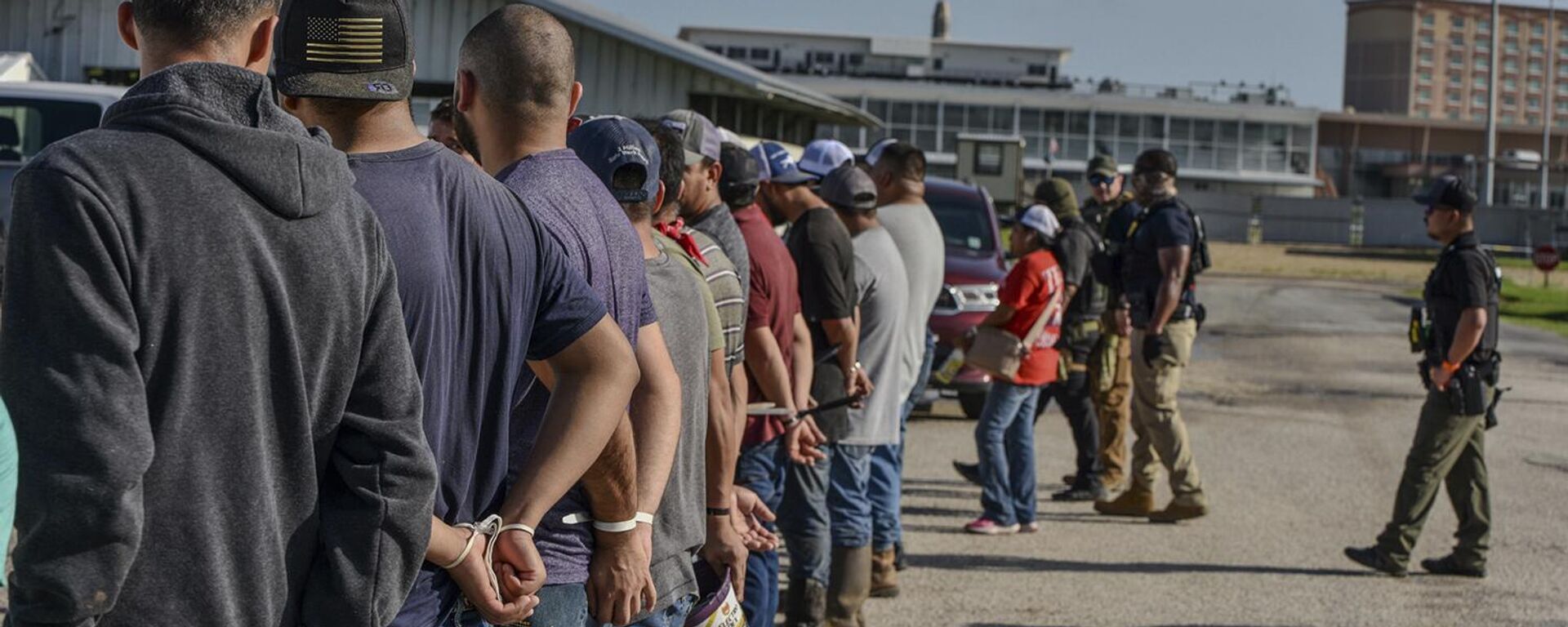 Trabajadores esposados después de ser arrestados por agentes del Servicio de Inmigración y Control de Aduanas de Estados Unidos - Sputnik Mundo, 1920, 26.06.2025