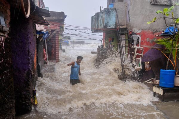 Un hombre observa cómo las olas causadas por la marea alta golpean su casa en la orilla del mar Arábigo en la ciudad de Bombay, la India. Un hombre observa cómo las olas causadas por la marea alta golpean su casa en la orilla del mar Arábigo en la ciudad de Bombay, la India. - Sputnik Mundo