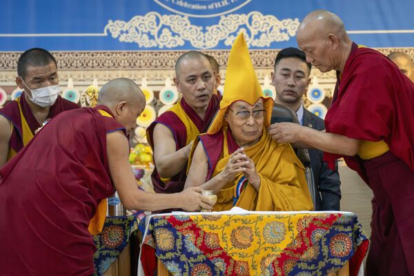 Los monjes asistentes ayudan al líder espiritual tibetano, el Dalái lama, a ponerse su gorro ceremonial mientras preside un evento para conmemorar su 90.° cumpleaños, según el calendario tibetano, en el templo Tsuglagkhang en Dharamsala, India. El cumpleaños del líder tibetano cae el 6 de julio, según el calendario gregoriano utilizado en la mayor parte del mundo. Los monjes asistentes ayudan al líder espiritual tibetano, el Dalái lama, a ponerse su gorro ceremonial mientras preside un evento para conmemorar su 90.° cumpleaños, según el calendario tibetano, en el templo Tsuglagkhang en Dharamsala, India. El cumpleaños del líder tibetano cae el 6 de julio, según el calendario gregoriano utilizado en la mayor parte del mundo. - Sputnik Mundo