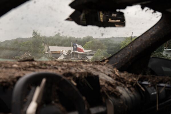 Una bandera de Texas se ve entre los restos de un vehículo destruido por las inundaciones. Una bandera de Texas se ve entre los restos de un vehículo destruido por las inundaciones. - Sputnik Mundo