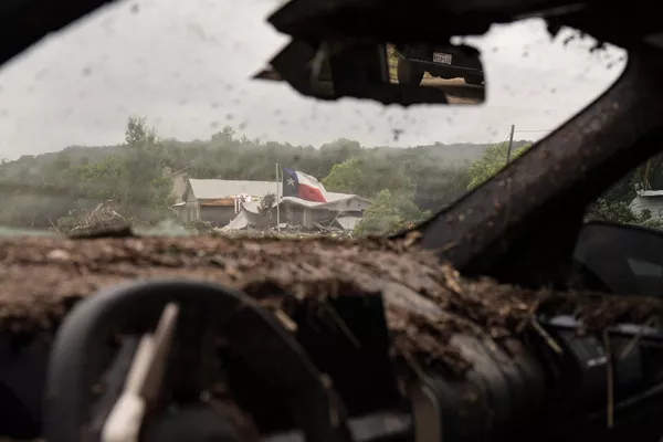 Una bandera de Texas se ve entre los restos de un vehículo destruido por las inundaciones. - Sputnik Mundo