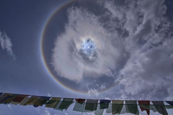 Banderas budistas de oración ensartadas en una carretera se ven contra el sol de primera hora de la tarde, alrededor del cual aparece un halo atmosférico en la localidad de Tangtse, en la India. - Sputnik Mundo