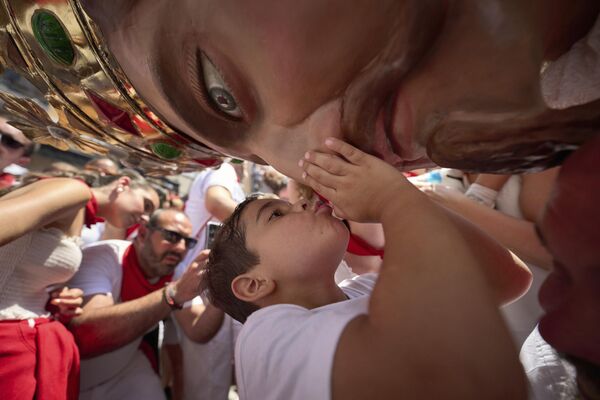 Un niño besa una figura con cabeza grande en el festival de San Fermín en Pamplona. - Sputnik Mundo