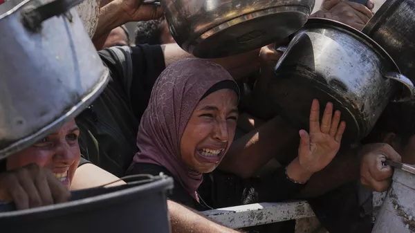 Palestinos luchan por conseguir alimentos donados en un comedor comunitario en la ciudad de Gaza, al norte de la Franja de Gaza, el sábado 26 de julio de 2025. (Foto AP/Abdel Kareem Hana) - Sputnik Mundo