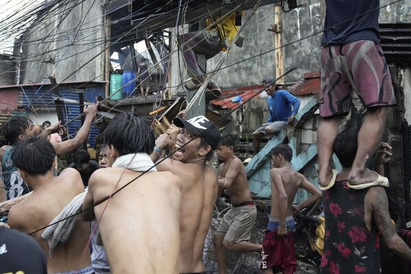 Filipinos recogen cables eléctricos tras un incendio que arrasó un barrio pobre de Manila, la capital del país. - Sputnik Mundo