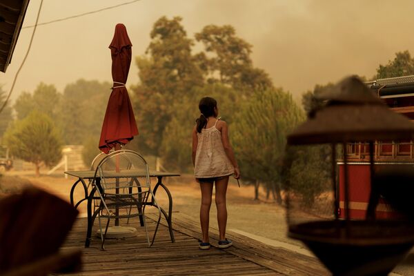 Una joven observa desde la terraza cómo los bomberos combaten los incendios que asolan el estado estadounidense de California. - Sputnik Mundo