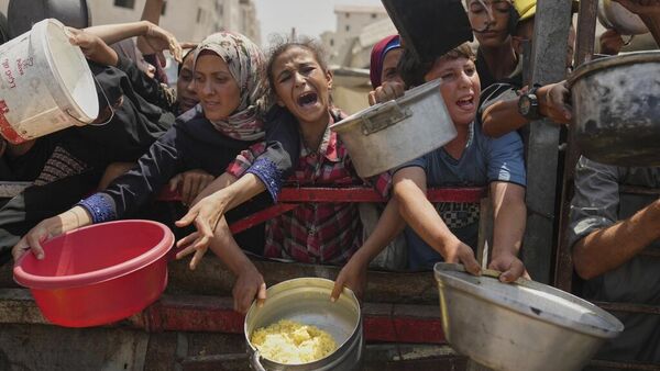 Los palestinos luchan por conseguir alimentos donados en una cocina comunitaria en la ciudad de Gaza, al norte de la Franja de Gaza  - Sputnik Mundo