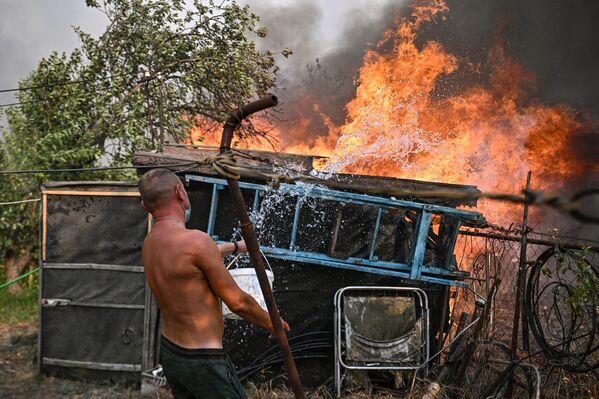 Un hombre apaga un incendio en la localidad de Oljovskie Dachi, en el distrito de Stanichno-Lugansk, en la república popular de Lugansk.  - Sputnik Mundo