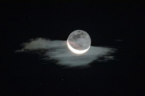 Luna creciente iluminada por la luz de la Tierra se ve sobre una nube en el cielo antes del amanecer, en China. - Sputnik Mundo