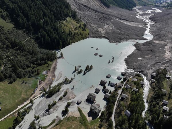 En esta vista aérea, las casas yacen sumergidas cerca de rocas, grava y hielo depositados por el deslizamiento de tierra en la comuna de Blatten, Suiza.El 28 de mayo, tras varios días de pequeños desprendimientos, millones de metros cúbicos de rocas cayeron desde la montaña Kleines Nesthorn sobre el glaciar Birch, provocando que una gran mezcla de rocas, hielo y barro se estrellara contra el valle de Lotschental.Gran parte del pueblo de Blatten quedó destruido. Las autoridades ya habían evacuado la localidad y los asentamientos más arriba en el valle la semana anterior. - Sputnik Mundo