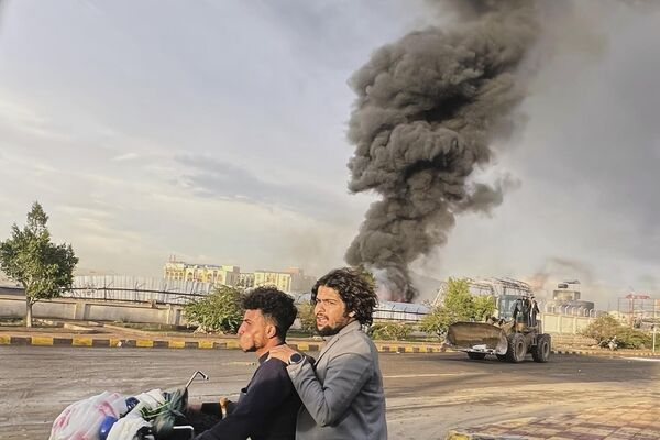 La gente maneja motocicleta mientras el humo se eleva tras los ataques aéreos israelíes en varias zonas, entre ellas una central eléctrica y una gasolinera en la capital de Yemen, Saná. - Sputnik Mundo