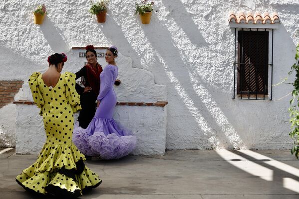 Mujeres vestidas con trajes de flamenco pasean por el Cortijo de Torres en la Feria de Málaga, en Andalucía, España.  - Sputnik Mundo
