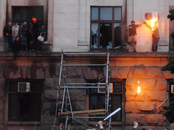 Personas salieron al cornisamento durante el incendio en la Casa de los Sindicatos en Odesa. A la derecha: el rostro y el cabello de una joven fueron alcanzados por un trapo empapado en mezcla inflamable proveniente de una botella de cóctel Molotov lanzada. - Sputnik Mundo
