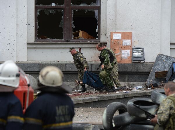 Milicianos populares transportan a una víctima mortal del ataque aéreo de la Fuerza Aérea de Ucrania contra el edificio de la administración regional en Lugansk. - Sputnik Mundo