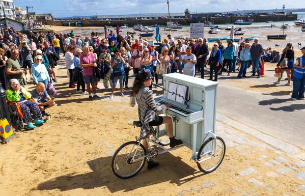 El público se reúne para ver la actuación de la pianista itinerante Chloe Marie Aston, conocida como Piano Bike Girl, en el Reino Unido. - Sputnik Mundo