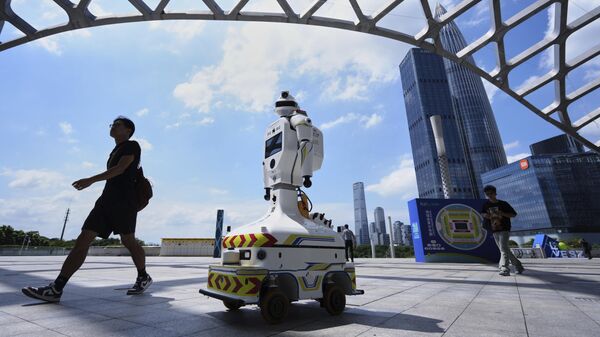 La gente pasa junto a un robot policial equipado con una cámara de videovigilancia en el estadio de un centro deportivo, en la provincia de Guangdong, China - Sputnik Mundo