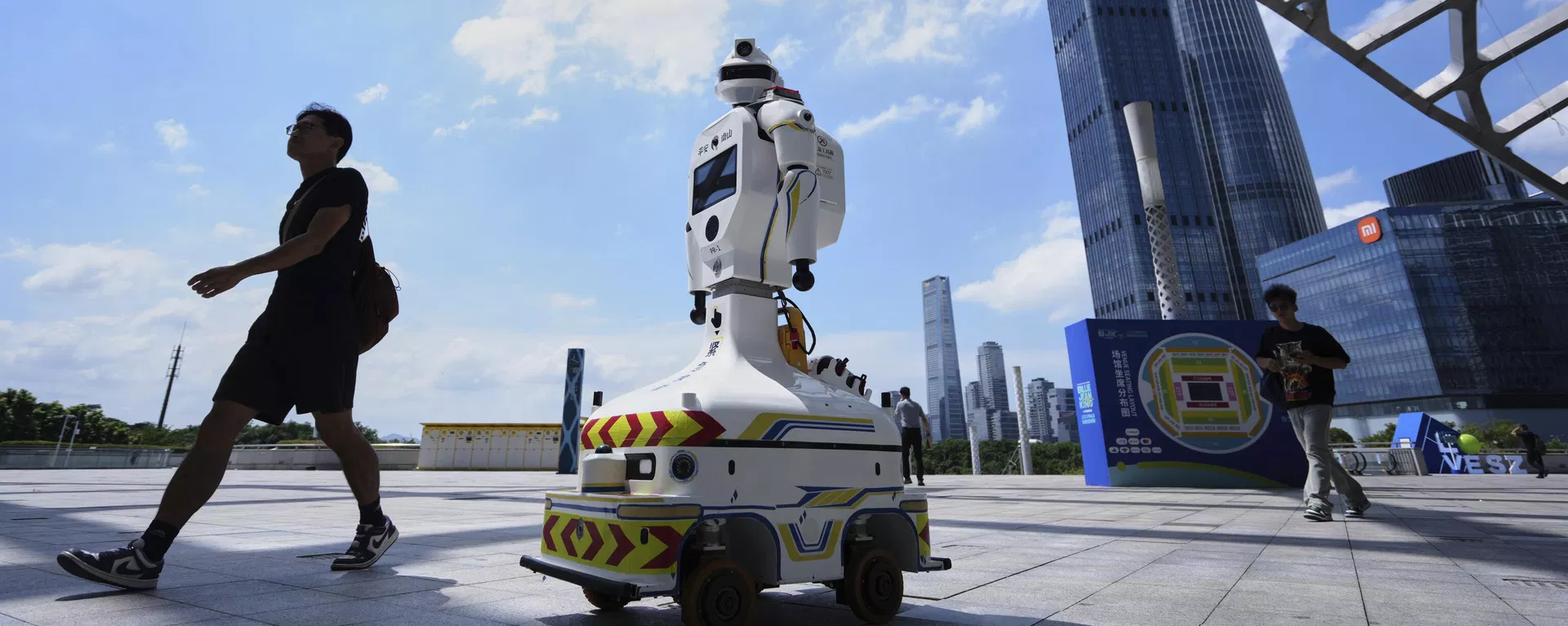 La gente pasa junto a un robot policial equipado con una cámara de videovigilancia en el estadio de un centro deportivo, en la provincia de Guangdong, China - Sputnik Mundo, 1920, 06.08.2026