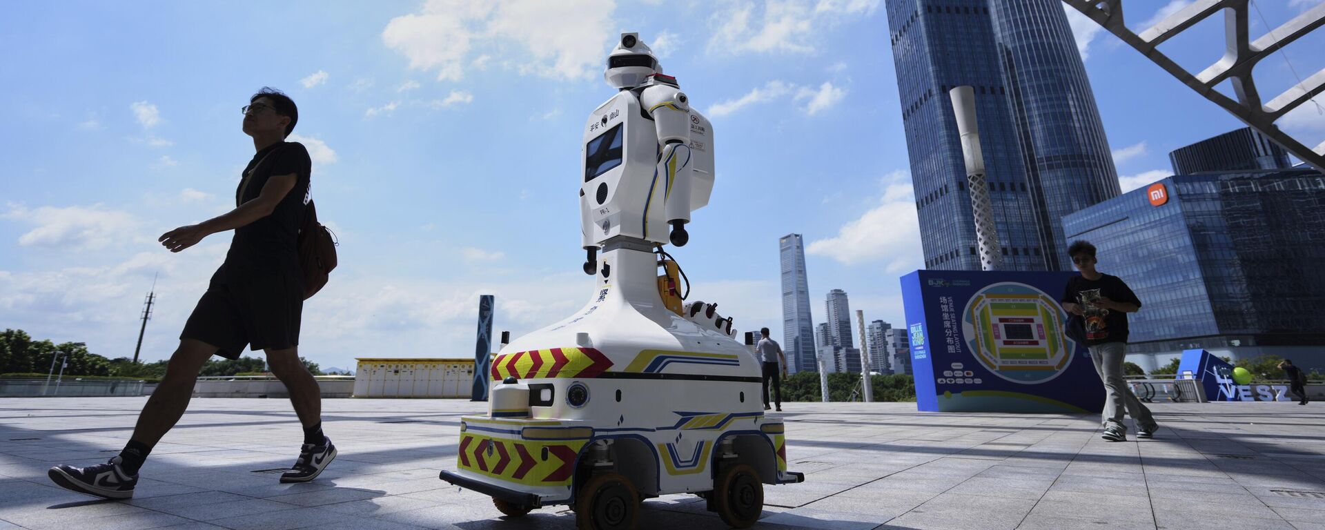 La gente pasa junto a un robot policial equipado con una cámara de videovigilancia en el estadio de un centro deportivo, en la provincia de Guangdong, China - Sputnik Mundo, 1920, 03.05.2026
