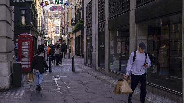 Un hombre carga bolsas de compras mientras camina cerca de Carnaby Street, en Londres, el 22 de marzo de 2023 - Sputnik Mundo