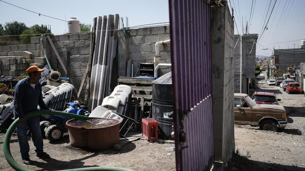 Un trabajador entrega agua a una vivienda en Iztapalapa, a las afueras de la Ciudad de México, el miércoles 6 de marzo de 2024. La extensa Ciudad de México obtiene su agua de acuíferos subterráneos sobreexplotados y de una vasta red de canales, presas y embalses llamada el Sistema Cutzamala. (Foto AP/Eduardo Verdugo) - Sputnik Mundo